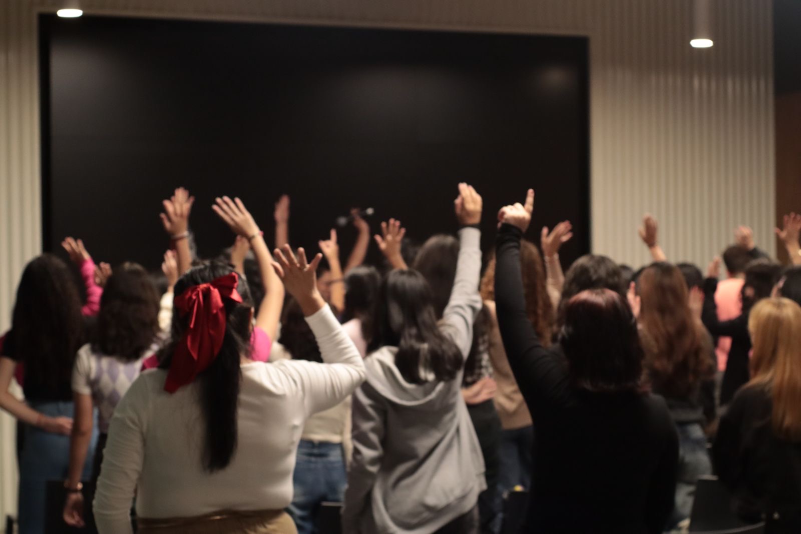 Participantes levantan la mano durante una sesión de MenTe en Acción