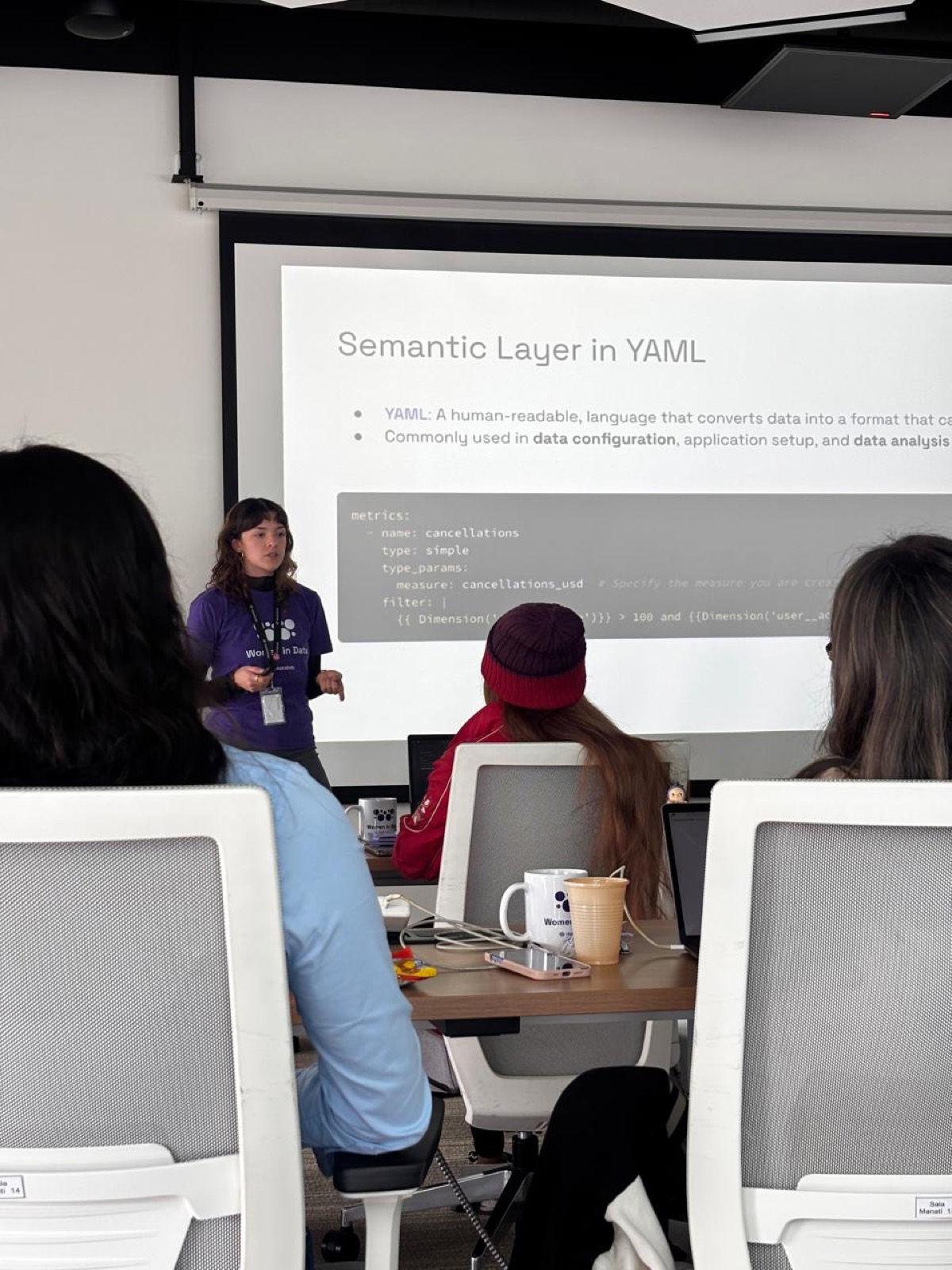Una facilitadora explica análisis de datos frente a un grupo con computadoras