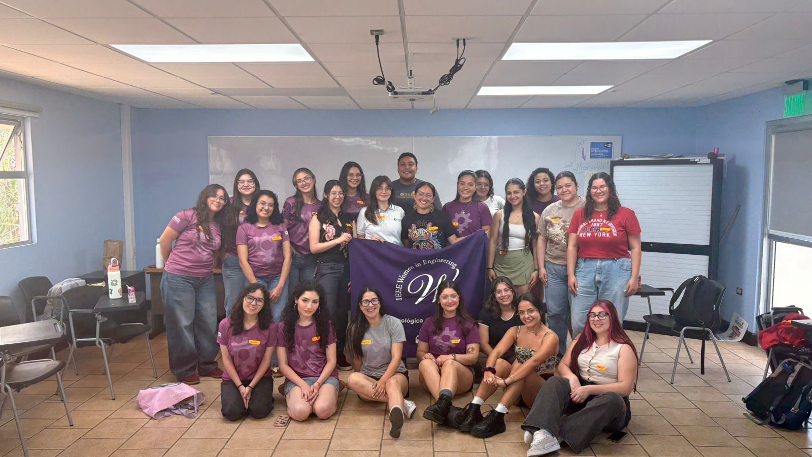 Grupo de participantes junto a la bandera de IEEE Women in Engineering