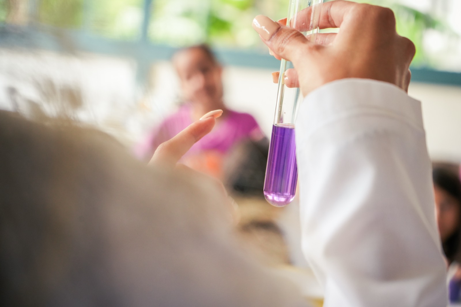 Una niña sostiene un tubo de ensayo con líquido morado durante un experimento