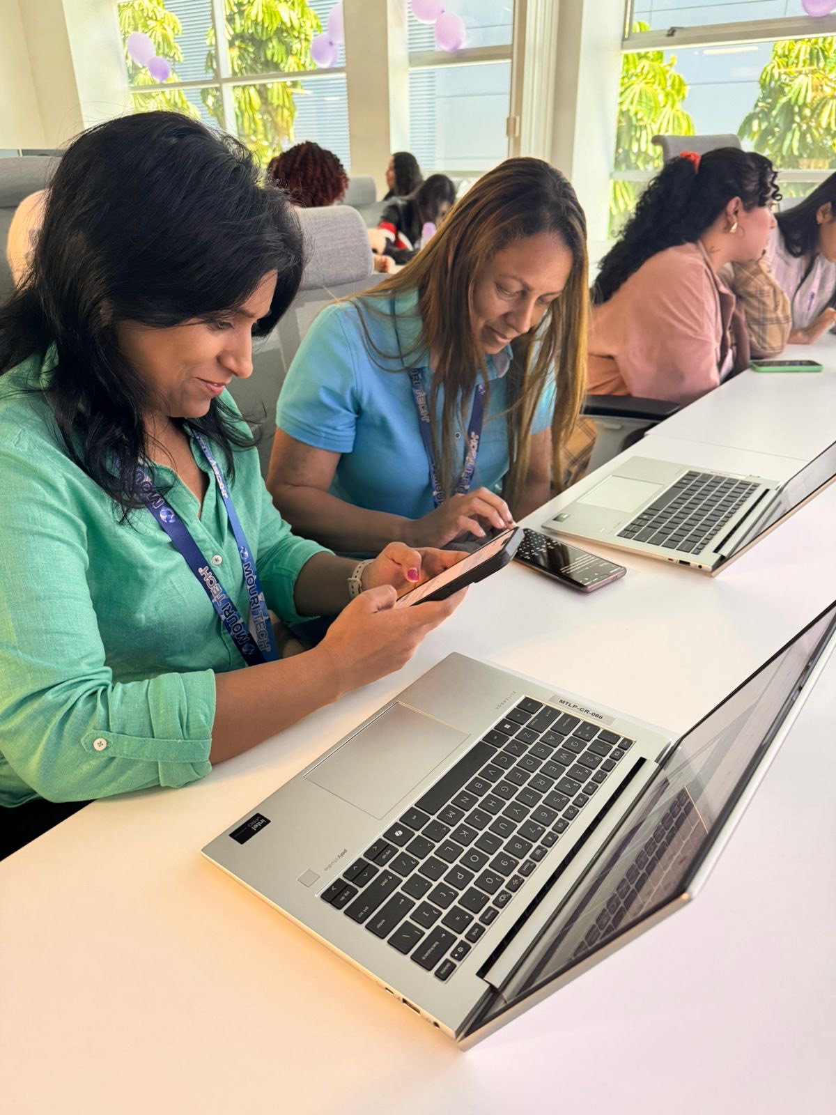 Dos participantes trabajan con sus computadoras durante una capacitación